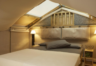 Innenraum eines luxuriösen Glamping-Zelts bei Lago Idro Glamping Boutique Lombardei mit Doppelbett.