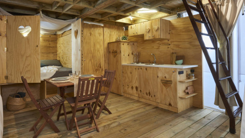 Houten interieur van glamping accommodatie bij Lago Idro Glamping Boutique met eettafel en kitchenette.