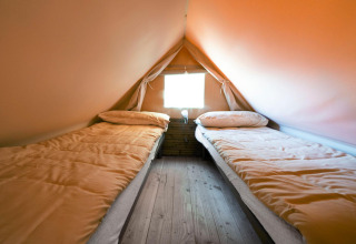 Interieur van een glamping tent met twee eenpersoonsbedden en houten vloer bij Lago Idro Glamping Boutique in Italië.