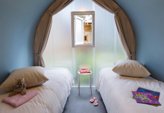 Vue intérieure d'une tente glamping au Lago Idro Glamping Boutique avec deux lits simples et une fenêtre.