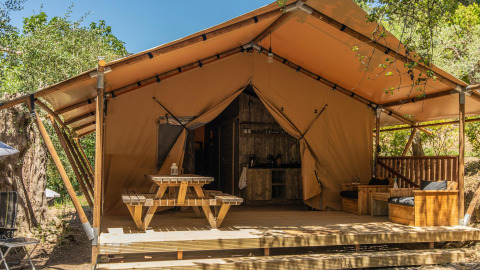 Glamping accommodatie bij Lago Idro Glamping Boutique met houten terras, picknicktafel en safaritent.