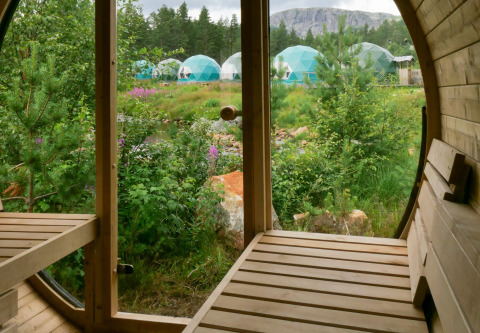 Vue depuis un sauna en bois sur la verdure et les dômes de glamping à Brokkestøylen, Agder.