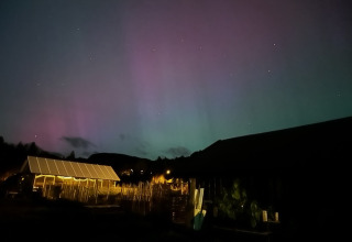 Glamping at Brokkestøylen Domes in Agder, glowing tent under northern lights in a tranquil night scene.