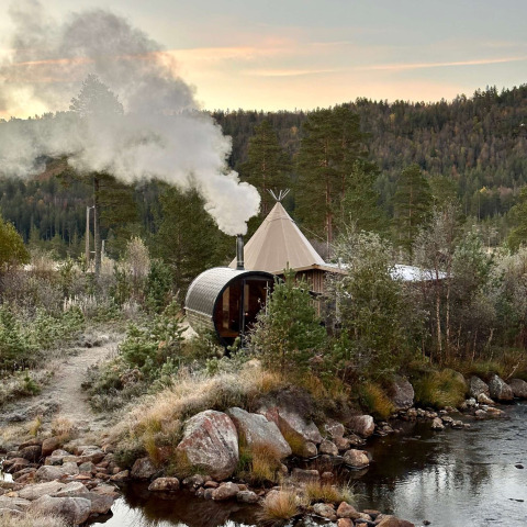 Glampingindkvartering Brokkestøylen - Domes i Agder, omgivet af skov og en bæk ved solnedgang.