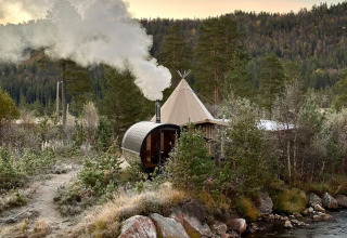 Glampingaccommodatie Brokkestøylen - Domes in Agder, omringd door bos en een beekje bij zonsondergang.