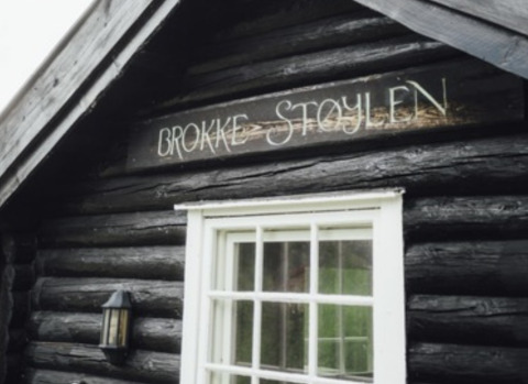 Wooden cabin with a 'Brokke Støylen' sign above the window, glamping accommodation or camping in Agder.