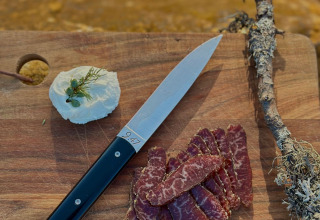 Tagliere con carne affettata, formaggio alle erbe e coltello a Brokkestøylen - Domes in Agder glamping.