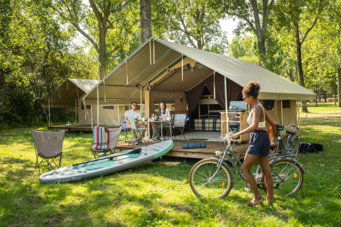 Glamping accommodatie bij Huttopia Lac d’Aureilhan – Mimizan, Nouvelle-Aquitaine, met ontspannende gasten buiten.