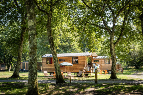 Glamping-Unterkunft in Holzhütten unter Bäumen bei Huttopia Lac d’Aureilhan – Mimizan, Nouvelle-Aquitaine.