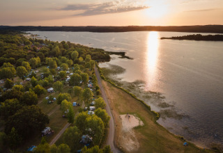Aerial view of Huttopia Lac d’Aureilhan – Mimizan glamping site by the lake at sunset in Nouvelle-Aquitaine.