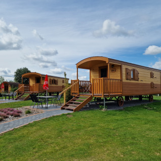 Glampinghytter på Campingplatz Auf dem Simpel Pipowagen, med grønne arealer og udendørs siddepladser.
