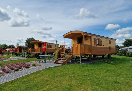 Cabañas de glamping en Campingplatz Auf dem Simpel - Pipowagen Alemania, rodeadas de césped y mesas.