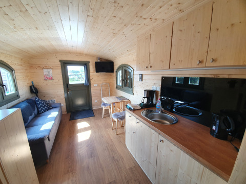 Binnenaanzicht van Campingplatz Auf dem Simpel Pipowagen met houten wanden, kitchenette en zitgedeelte.