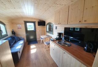 Innenansicht von Campingplatz Auf dem Simpel Pipowagen mit Holzausstattung, Küchenzeile und Sofa.