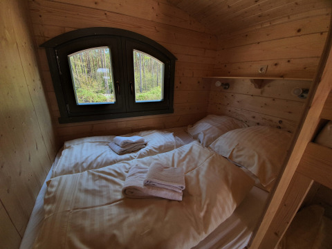 Acogedora cabaña de madera con cama doble y ventana, glamping en Campingplatz Auf dem Simpel, Pipowagen Duitsland.