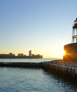 Atardecer en Koudekerke-Dishoek, Zeeland, Países Bajos, con un faro y un barco portacontenedores en el puerto.