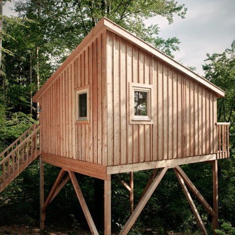 Houten boomhut als glamping-accommodatie bij Wipfelglück Baumhaushotel, Boomhut Beieren, tussen bomen.