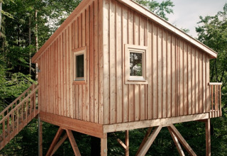 Cabane en bois pour glamping au Wipfelglück Baumhaushotel, Boomhut Beieren, entourée de forêt verdoyante.