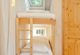 Cozy bunk beds inside Wipfelglück Baumhaushotel, with wooden interior and large windows for sunlight.