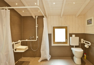 Handicapvenligt badeværelse i Wipfelglück Baumhaushotel med brusebad, toilet og støttegreb