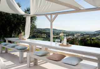 Zona pranzo esterna con tavoli e panche bianche sotto pergolato, vista panoramica di Le Marche, Villa la Diva.