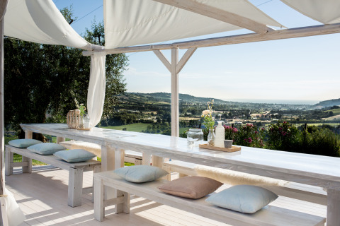 Buiten eethoek met lange witte tafels en banken, kussens, onder doek met uitzicht op Le Marche, Villa la Diva.