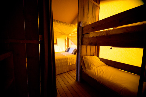 Interno glamping Villa la Diva - Safaritenten Le Marche con letto matrimoniale e letto a castello in legno.
