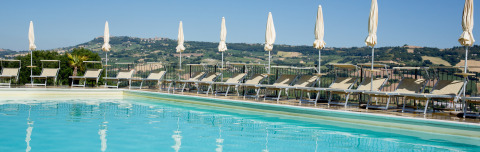 Piscine avec transats et parasols à Villa la Diva - Safaritenten Le Marche, hébergement glamping en Italie