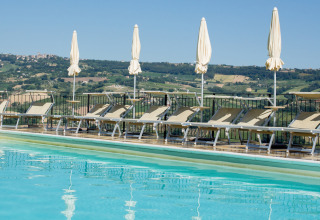 Piscine avec transats et parasols à Villa la Diva - Safaritenten Le Marche, hébergement glamping en Italie