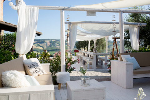 Luxury outdoor lounge and dining space with canopy seating and hill views at Villa la Diva Le Marche glamping.