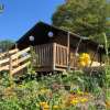 Camping Groß-Eichen glamping with safari tents, wooden deck, and wildflowers in sunny Hessen, Germany.