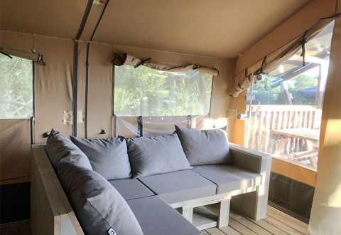 Vue intérieure d'une tente safari avec canapé moderne et grandes fenêtres au Camping Groß-Eichen, Hessen.