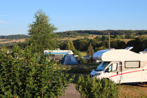 Campsite with motorhomes, tents, and green landscape at Camping Groß-Eichen - Safaritenten Hessen in sunlight.