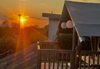 Zonsondergang bij glampingaccommodatie met houten terras, Camping Groß-Eichen - Safaritenten Hessen.