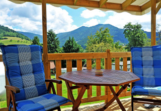 Acogedora terraza con sillas azules y mesa de madera, vistas a las montañas en Camping Schwarzwaldhorn, glamping.