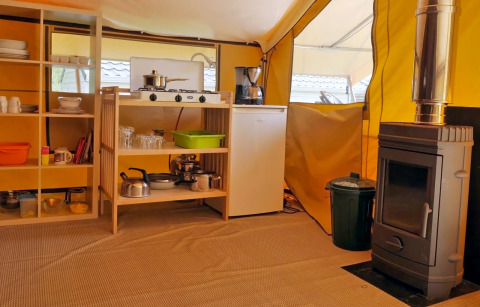 Indvendigt billede af glamping-køkken med komfur, køleskab og brændeovn på Camping Schwarzwaldhorn.