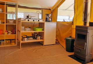 Binnenaanzicht van glampingkeuken met fornuis, koelkast en houtkachel bij Camping Schwarzwaldhorn.