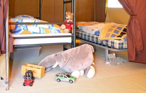 Binnenkant glamping bij Camping Schwarzwaldhorn met bedden, knuffeldieren en kinderspeelgoed op de vloer.