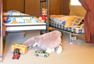 Binnenkant glamping bij Camping Schwarzwaldhorn met bedden, knuffeldieren en kinderspeelgoed op de vloer.