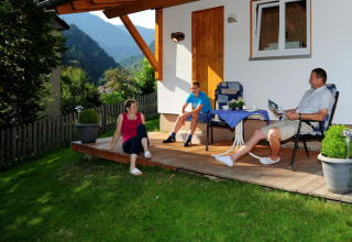 Familia relajándose en la terraza del camping Schwarzwaldhorn - Glamping Baden-Württemberg con paisaje montañoso.