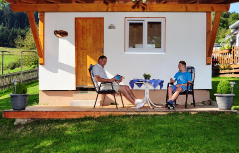 Twee mensen zitten ontspannen voor een glampingaccommodatie bij Camping Schwarzwaldhorn in Baden-Württemberg.