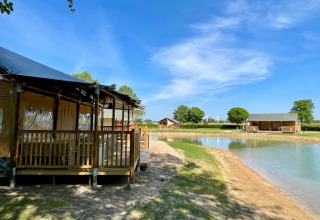 Glamping-indkvartering ved en sø hos De Betuwse Hofjes - Betuwe Lodges i Gelderland, Holland, under blå himmel.