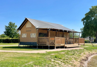 Hébergement glamping au bord du lac chez De Betuwse Hofjes - Betuwe Lodges Gelderland sous un ciel bleu clair.