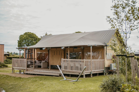 Glamping-Unterkunft bei De Betuwse Hofjes - Betuwe Lodges in Gelderland mit geräumiger Veranda und Sitzgelegenheiten.