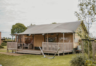 Glamping accommodatie bij De Betuwse Hofjes - Betuwe Lodges in Gelderland, met veranda en loungeset buiten.