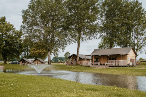 Glamping en De Betuwse Hofjes - Betuwe Lodges Gelderland, tiendas y cabañas junto a estanque con fuente.