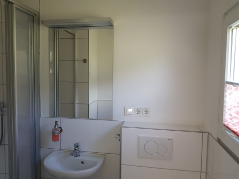 Modernes Badezimmer mit Spiegel, Waschbecken, Dusche, Fenster und Steckdosen im Camping im Bergischen Land.