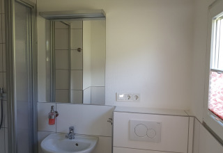 Modern bathroom with mirror, sink, shower, window, and wall sockets at Camping im Bergischen Land accommodation.