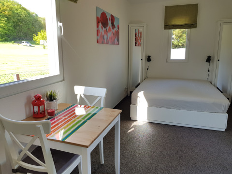 Luminoso alloggio glamping al Camping im Bergischen Land con letto matrimoniale e tavolo vicino alla finestra.