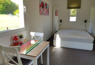 Lyst og hyggeligt glampingværelse på Camping im Bergischen Land med dobbeltseng og spisebord.